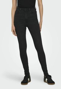 Pantalones vaqueros negros de tiro alto con corte slim y un ligero estiramiento. Cuenta con cinco bolsillos, trabillas para el cinturón y una textura suave y mate.