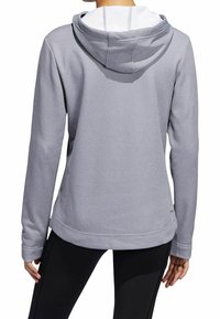 Sudadera de color gris claro con tejido texturizado, forro interior blanco y un ajuste relajado. Cuenta con capucha ajustable y mangas largas.
