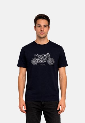 Mladý muž v čiernom tričku s bielou čiarovou kresbou motocykla a textom "San Diego California Motor County."