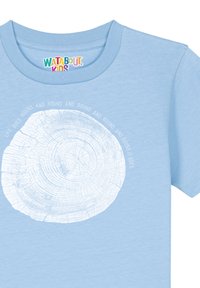 T-shirt en coton bleu clair avec un graphisme de rond de bois blanc comportant des cercles concentriques et le texte : "La vie tourne en rond et ça tourne encore."