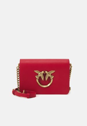 Sac à main en cuir rouge avec une fermeture circulaire en métal doré ornée de deux oiseaux. Comprend une bandoulière en chaîne et une bandoulière en cuir amovible.