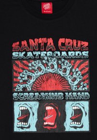 T-shirt preta com um design gráfico multicolorido apresentando o texto "Santa Cruz Skateboards", bocas a gritar e um padrão central de raios de sol.
