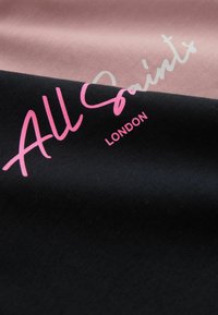 Schwarzer und rosa Baumwollstoff mit dem Text "All Saints" in Pink und Weiß, mit einer glatten, strukturierten Oberfläche und verschiedenen Farbbereichen.