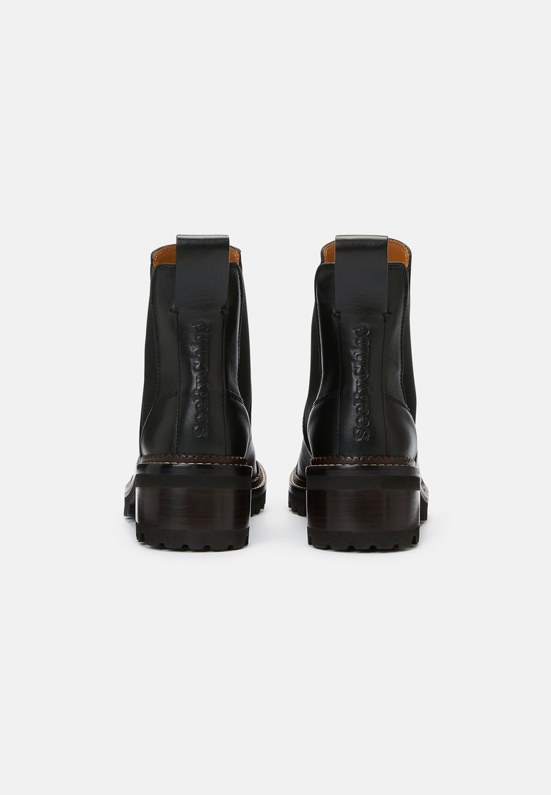 Bottines noires en cuir avec une semelle épaisse marron, présentant une finition lisse, des panneaux latéraux élastiques et des languettes pour un enfilage facile.