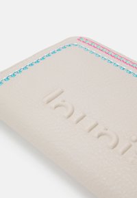 Helles beiges Lederportemonnaie mit geprägtem Logo und bunten Nähten in Blau und Pink entlang der Kanten, mit einer strukturierten Oberfläche.