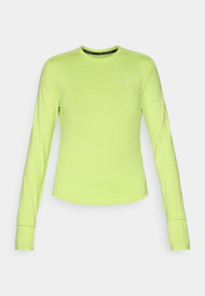 Camisa desportiva de manga longa em verde brilhante. Feita de um tecido leve com uma textura suave e bainha arredondada. Apresenta um pequeno logótipo.