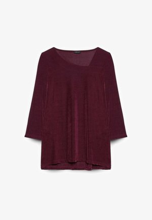 Top burdeos de manga larga con cuello redondo y corte relajado. Textura suave con un brillo sutil y aberturas laterales en el dobladillo.