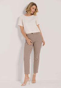 Licht beige short-sleeve top gecombineerd met taupe slim-fit broek en beige enkelbandjes hakken. Gladde stof, op maat gemaakte pasvorm, minimalistisch ontwerp.