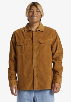 Brown corduroy shirt with two front pockets, button closure, and a collared neckline. Features a textured, ribbed pattern.