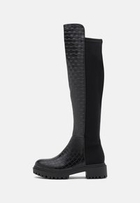 Bottes noires montant jusqu'aux genoux avec une texture tissée sur le devant, un dos lisse, et une semelle épaisse avec un talon légèrement surélevé.