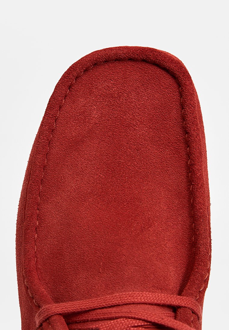 Rote Wildleder-Schuhe mit runder Zehenpartie, sichtbaren Nähten und passenden Schnürsenkeln. Glatte Textur mit einem schlichten Design, ohne zusätzliche Verzierungen.