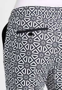 Marina- och vitmönstrade byxor med geometriskt tryck, bakficka och svarta knappar som detalj. Tillverkade av ett slätt, strukturerat tyg.