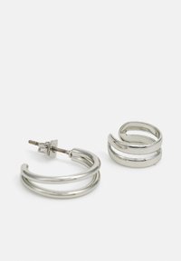 Pendientes de aro de plata con un diseño de doble lazo, que cuentan con un acabado pulido y un cierre de presión para un ajuste seguro.