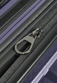 Valigia espandibile con una finitura testurizzata di color viola scuro. Presenta una zip nera con la scritta "Expandable" incisa, circondata da accenti di tessuto intrecciato.