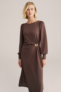 Brązowa, teksturowana sukienka z długimi bufiastymi rękawami, dopasowaną talią i złotym okrągłym akcentem. Projekt o długości do połowy łydki z delikatnym wzorem.