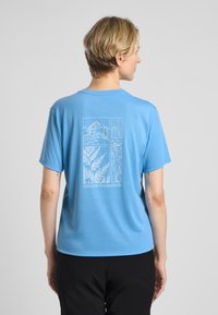 Light blue short-sleeve t-shirt featuring a detailed white graphic design on the back, including mountains and foliage patterns.