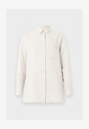 Λευκό πουκάμισο με μακριά μανίκια, κουμπιά, γιακά και μία τσέπη στο στήθος, εμφανίζεται σε απλό, ανοιχτό φόντο.