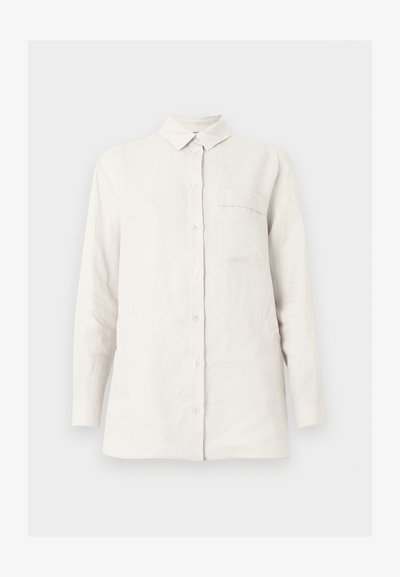 Λευκό πουκάμισο με μακριά μανίκια, κουμπιά, γιακά και μία τσέπη στο στήθος, εμφανίζεται σε απλό, ανοιχτό φόντο.
