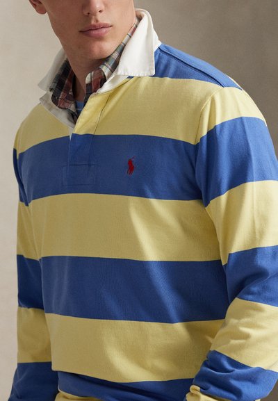 Ρουά και κίτρινη ριγέ ριγέ ριγέ ριγέ ριγέ ριγέ ριγέ ριγέ ριγέ ριγέ ριγέ ριγέ ριγέ ριγέ με λευκό γιακά. Διαθέτει ένα μικρό κόκκινο λογότυπο στο στήθος. Υλικό από βαμβάκι με ορατές ραφές.