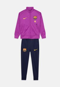 FC Barcelona sporta kostīms ar purpura krāsā apģērbtību ar zilu rāvējslēdzēja jaku un ziliem biksēm. Materiāls: poliesters. Akcenti ietver komandas logotipu un Nike swoosh dzeltenā krāsā.