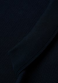 Navy modrý svetr z látky s texturovaným pleteným vzorem. Obsahuje hladký, žebrovaný límec a je vyroben z měkkého, pohodlného materiálu.