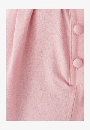 Světlé růžové tkaniny s texturovanou vazbou, zdobené knoflíkovým detailem v hladkém provedení a jemným nařasením podél okraje.