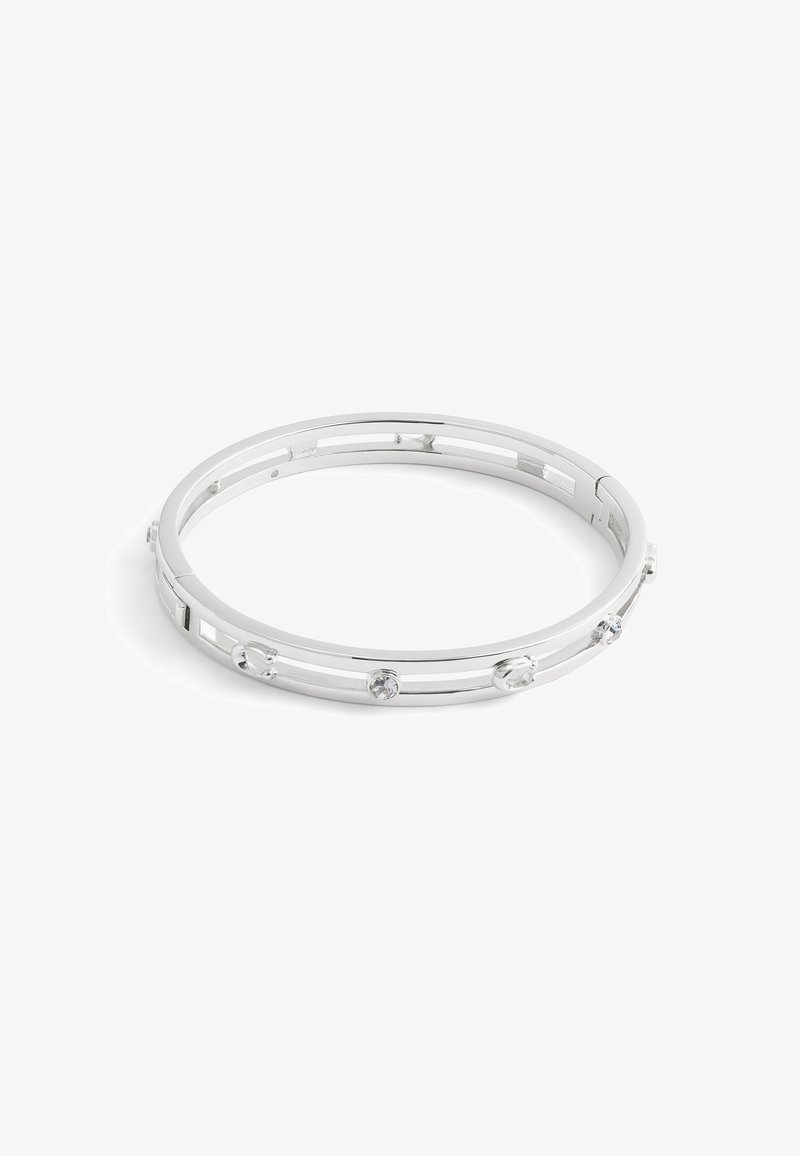 Bracelet jonc ton argent avec des cristaux ronds transparents espacés uniformément et un design ouvert avec une découpe rectangulaire sur fond blanc.