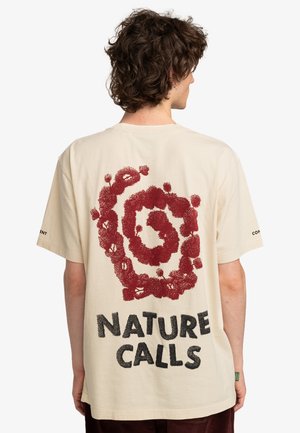 Beige Baumwoll-T-Shirt mit einem spiralförmigen Grafikdesign in Dunkelrot und schwarzem Text "NATURE CALLS" auf der Rückseite. Kurze Ärmel, lockere Passform.