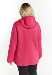 Giacca in pile rosa con cappuccio, finitura texturizzata, vestibilità rilassata e patch con logo sulla manica sinistra. Gli angoli hanno bordi smussati.