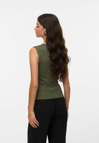 Oliven grønn ermel�øs topp med en tettsittende design og glatt tekstur, kombinert med svarte bukser. Enkel og minimalistisk stil.