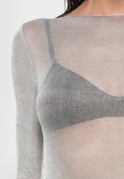 Top de manga larga de malla metálica plateada con una textura transparente, que presenta un escote redondeado y un sujetador negro debajo.