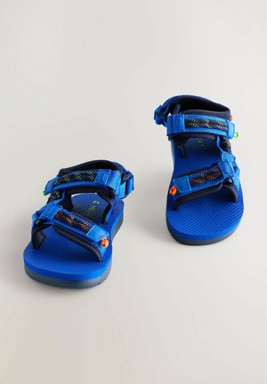 Plave sandale s podesivim trakama, teksturiranim gumenim đonovima i uzorkovanim gornjim dijelom s živopisnim naglasima. Lagani dizajn za vanjske aktivnosti.