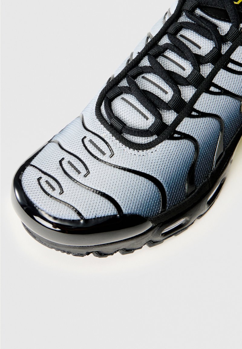 Schwarze und graue Sneakers mit einem Mesh-Obermaterial, abgerundetem Zeh und ausgeprägten, geschwungenen Linien an der Seite für Belüftung und Design. Gummisohle.