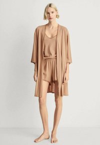 Vaaleanruskea vapaa-ajan asu, joka on valmistettu pehmeästä kankaasta. Settiin kuuluu löysä kimono-tyylinen bathrobe, toppi ja shortsit, joissa on pitsiä somistuksena.