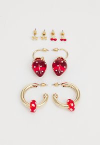 Red strawberry-shaped earrings with gold hardware, embellished with white dots, alongside gold stud earrings featuring bow and cherry designs.