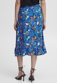 Blommig midikjol i klarblått med volangkant. Har färgglada blommor och en bekväm elastisk midja. Matchad med svarta klackar.