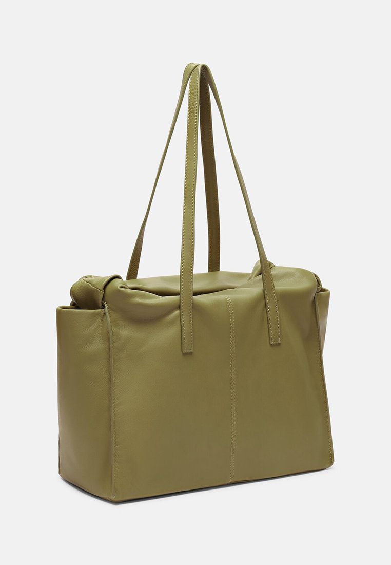 Oliwkowa skórzana torba tote z dwiema długimi rączkami, miękką strukturą i złożonym wierzchem. Gładka tekstura z minimalnymi detalami szewnymi.