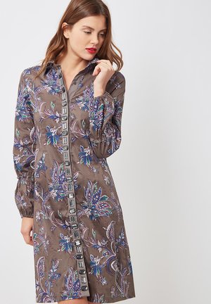 Vestido marrón con estampado de flores azules y verdes, con botones en la parte delantera, mangas largas con puños fruncidos. Tela ligera.