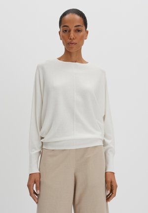 Haut en maille léger et blanc avec un col rond et des manches longues. Caractérisé par une coupe décontractée et une subtile couture au centre.