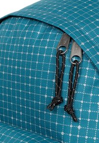Zaino in tessuto teal con motivo a griglia, dotato di doppie cerniere argento e tiranti neri. Materiale testurizzato con cuciture rinforzate.