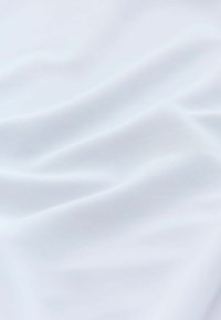 Vitt tyg med en slät, mjuk textur och lätt lyster. Materialet har en subtil stretch och minimala synliga mönster.