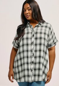 Camicia a maniche corte a quadri grigia e nera con bottoni. Presenta una vestibilità ampia e orlo arrotondato. Tessuto morbido con un design informale.