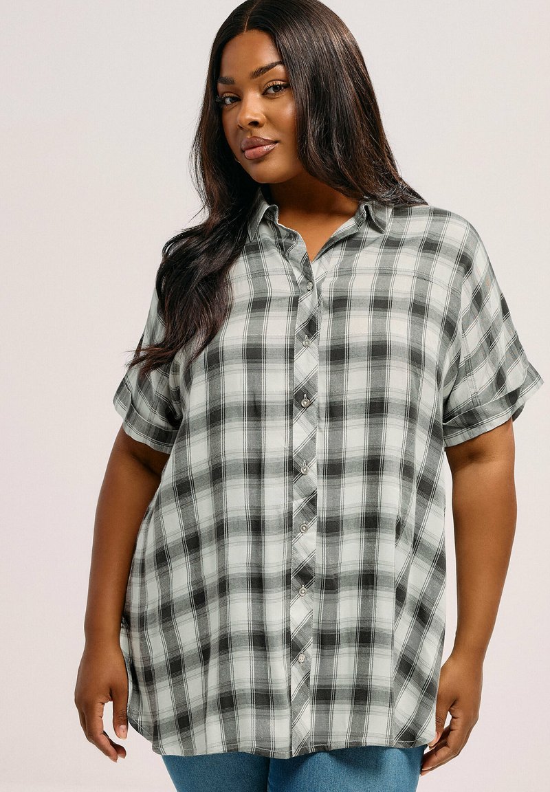 Camicia a maniche corte a quadri grigia e nera con bottoni. Presenta una vestibilità ampia e orlo arrotondato. Tessuto morbido con un design informale.