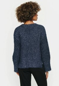 Textured navy blue sweater with a loose fit, fuzzy material, dropped shoulders, and uneven hemline. Suitable for casual wear.