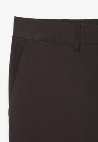 Donkerbruin katoenen broek met een zachte textuur, voorzien van een standaard tailleband, twee zijzakken en subtiele stikdetails.