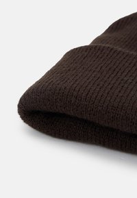 Brun strikket hue med ribbet tekstur og foldet manchet. Stoffet virker blødt og varmt, velegnet til koldt vejr.