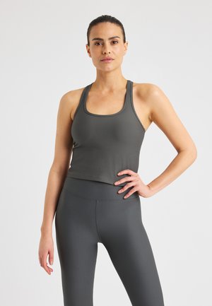 Canottiera atletica a coste di colore grigio scuro, con scollatura a cuore e spalline sottili, abbinata a leggings a vita alta coordinati.