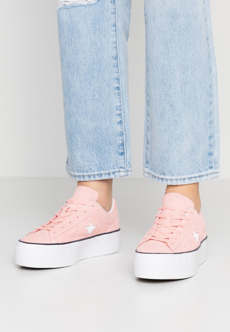 Baskets compensées en suède rose avec détail étoile blanche, dotées d'un design à lacets et d'une semelle en caoutchouc blanche, associées à un jean court bleu clair.