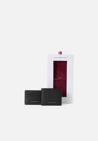Conjunto de carteira e porta-cartões pretos em material texturizado. Embalado numa caixa branca com interior vermelho e logótipo da marca na parte da frente.