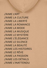 Felpa beige con testo nero che elenca frasi che iniziano con "J'aime" (Io amo), esprimendo apprezzamento per l'arte, la cultura e la bellezza.